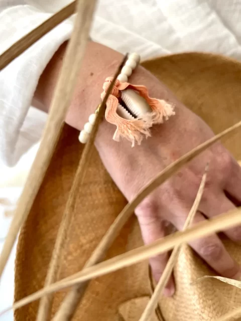 bracelet flow cauri est un bracelet élastique en bois fossile avec un coquillage cabri noué grâce à un gros lien saumon amovible