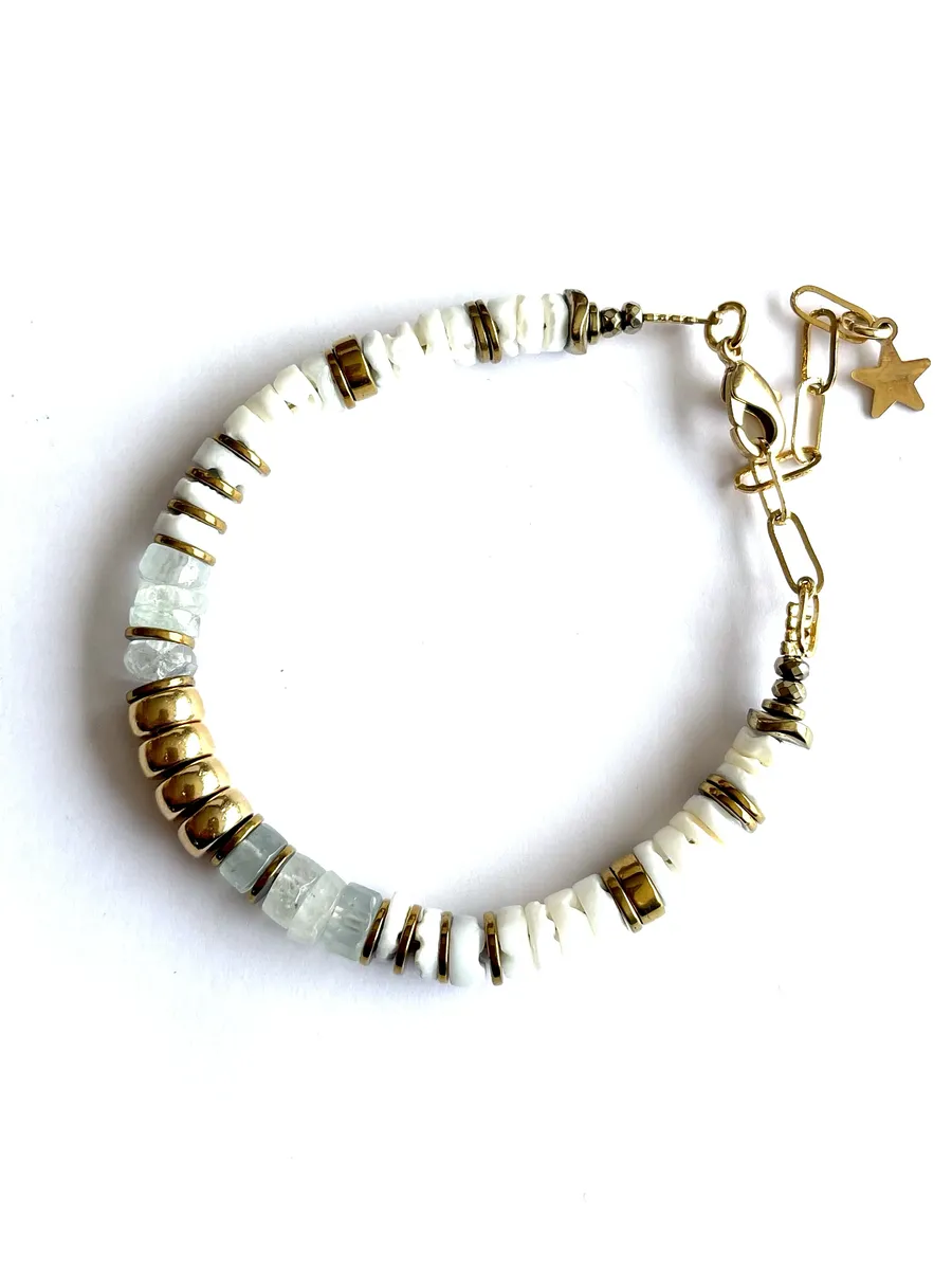 bracelet-nymphe-aigue-marine-fines-paulettequincaillerie-bijoux-créateur_27 bracelet nymphe aigue marine est un bracelet puka style surfeur chic en perles heishi en pierre d'aigues-marines marine à facettes et coquillages blanc avec une cartouche centrale en perles or