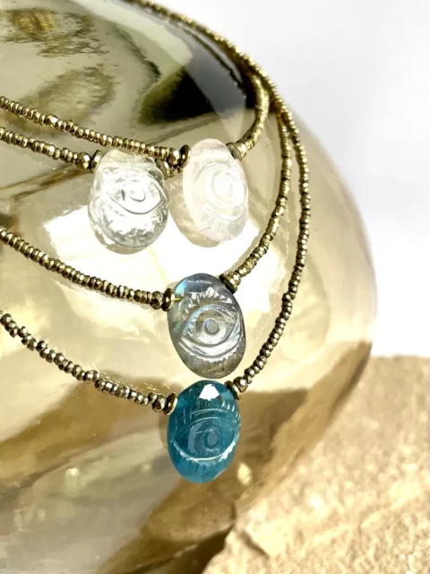 collier Horus est un ras de cou en hématites très fines très lumineuses or et un oeil sculpté en pierre au centre