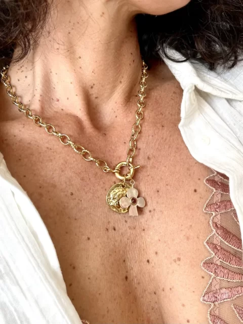collier lucky grenat nacre est un collier grosse maille doré à l'or fin 24k, avec un fermoir bouée xl et 2 pendentifs porte bonheur. Un trèfle en nacre rose et coeur grenat et une médaille grec ancienne