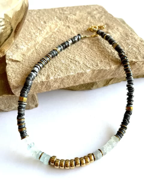 collier nymphe aigue marine bleu est un collier ras e cou style surfeur puka chic avec des perles heishi en coquillage et une cartouche centrale en aigue marine et perles plaqué or