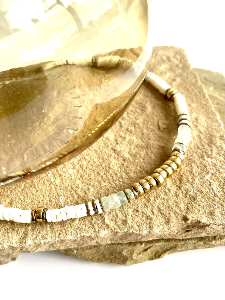 collier-nymphe-aigue-marine colier nymphe aigue marine est un collier puka style surfeur chic en coquillages blanc et perles heishi aigue marine à facettes et cartouche de perles centrales or