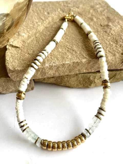colier nymphe aigue marine est un collier puka style surfeur chic en coquillages blanc et perles heishi aigue marine à facettes et cartouche de perles centrales or