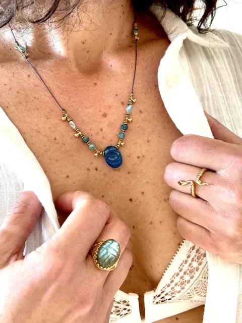 COLLIER HORUS SUR SOIE EST UN COLLIER REGLABEL EN SAUTOIR MONTÉE SUR UN CORDON DE SOIE AVEC DES PIERRES EN TURQUOISE ET UN OEIL EN PIERRE SCULPTÉ DE LABRADORITE