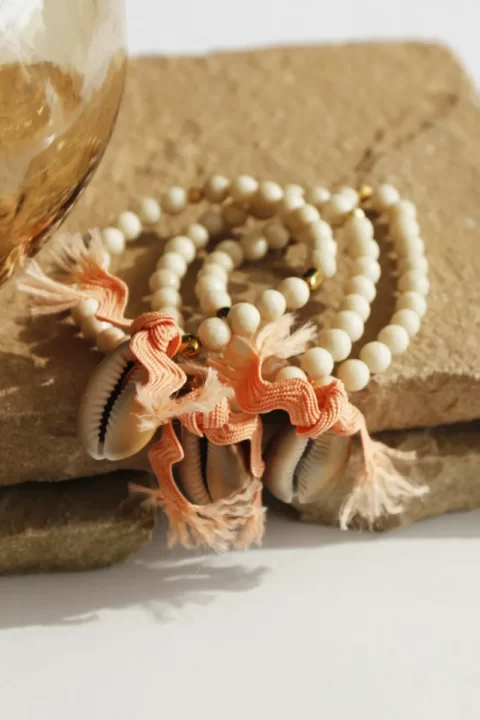 bracelet flow cauri est un bracelet élastique en bois fossile avec un coquillage cabri noué grâce à un gros lien saumon amovible